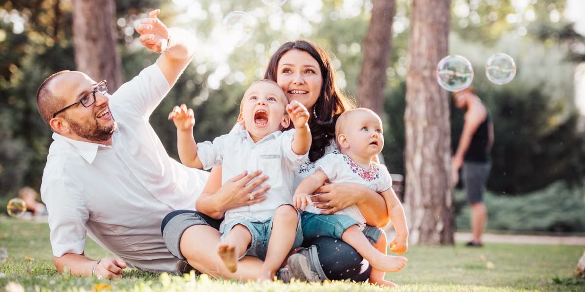 Joyful family enjoying a sunny day in the park while playing with bubbles.