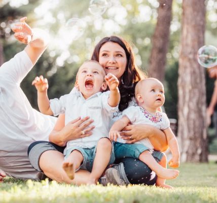 Joyful family enjoying a sunny day in the park while playing with bubbles.