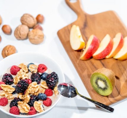A nutritious breakfast bowl featuring fresh berries and walnuts, served with sliced fruit and kiwi.