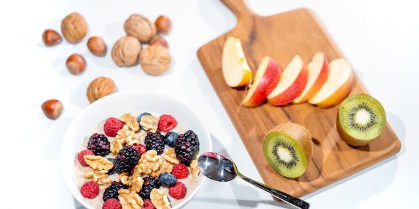A nutritious breakfast bowl featuring fresh berries and walnuts, served with sliced fruit and kiwi.