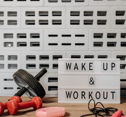 Fitness gear and motivational sign in home gym setup against a brick wall.