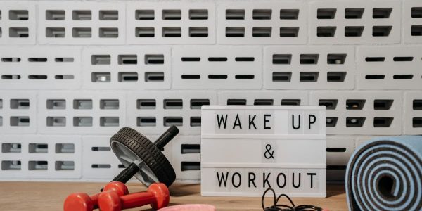 Fitness gear and motivational sign in home gym setup against a brick wall.